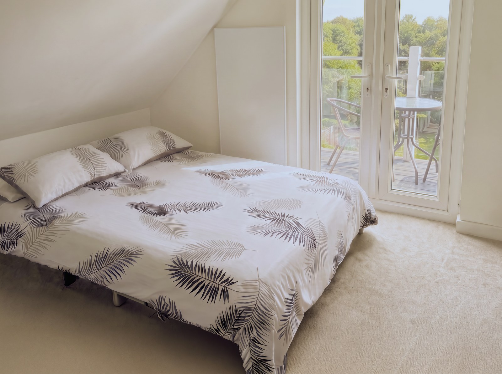 Double bed with the balcony doors alongside inside the studio apartment.